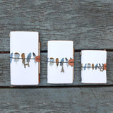 
three sizes of midori style traveler's notebook with boho feathers design on the wooden bench