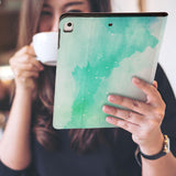 a girl is holding and viewing personalized iPad folio case with Abstract Watercolor Splash design 